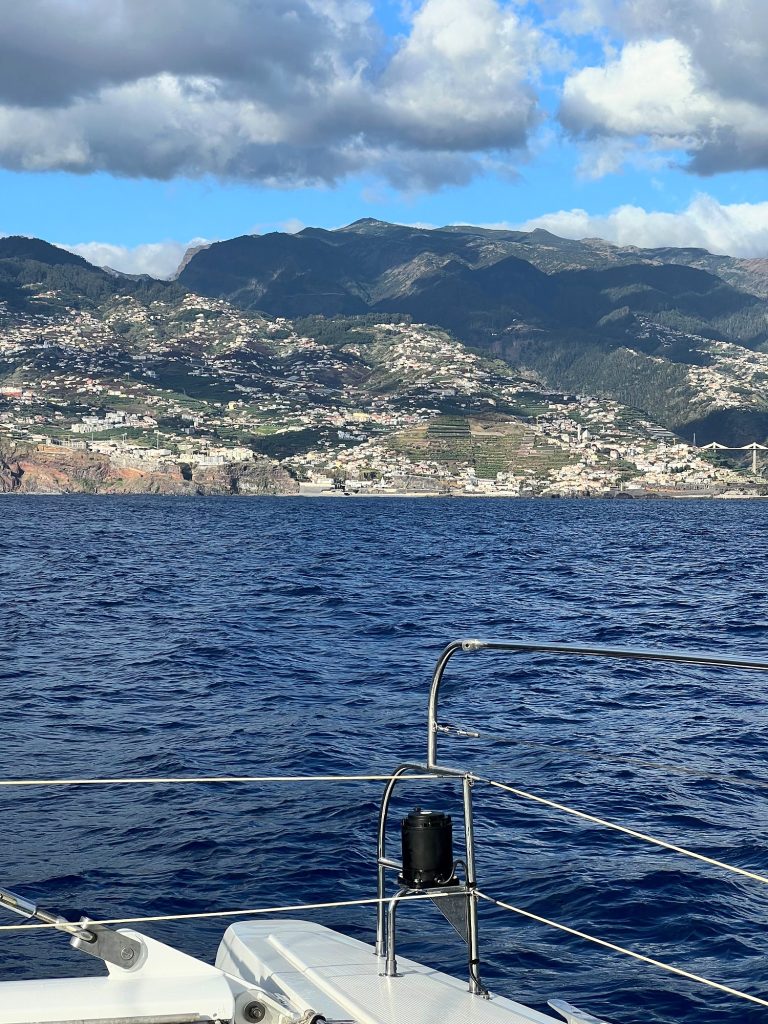 Bow of a catamaran with a railing and a view of Funchal from the ocean