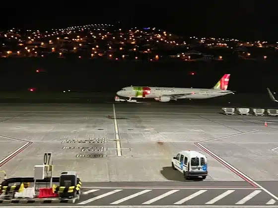 A TAP plane on the apron at Madeira Airport at night, with house lights on the hillside behind