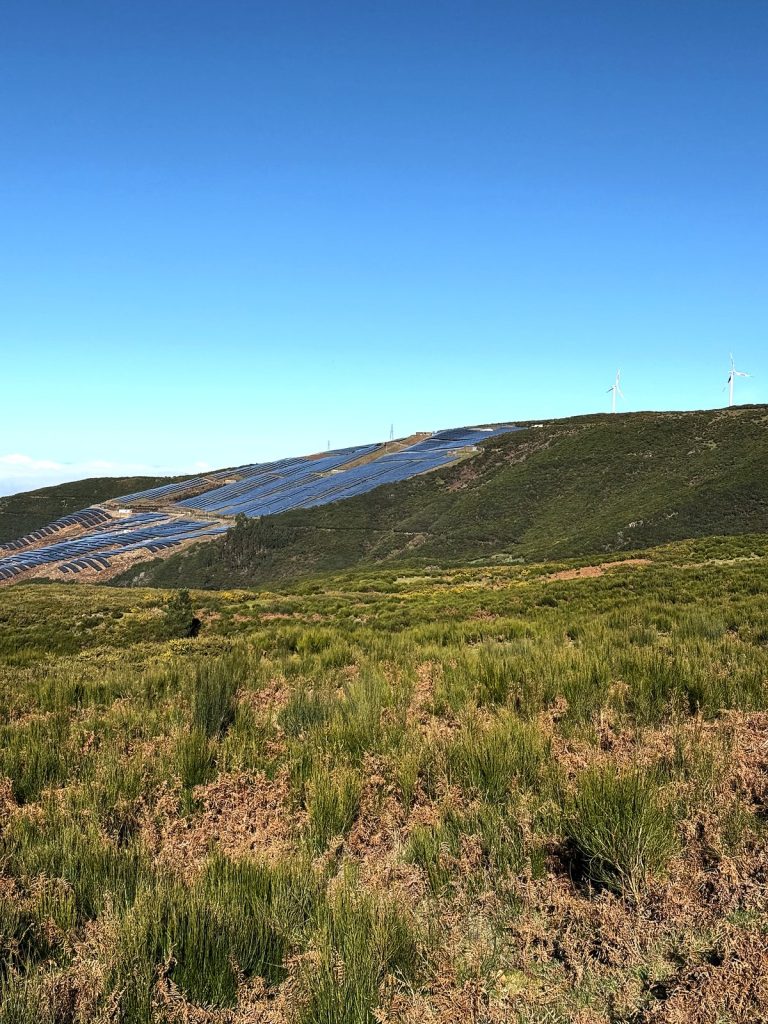 The Paul da Serra plateau covered in grass and heath, with solar panels and wind turbines on the slope behind