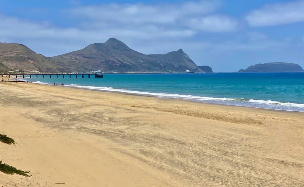 Wide sandy beach on Porto Santo with the pier and the islet of Ilhéu de Baixo in the background