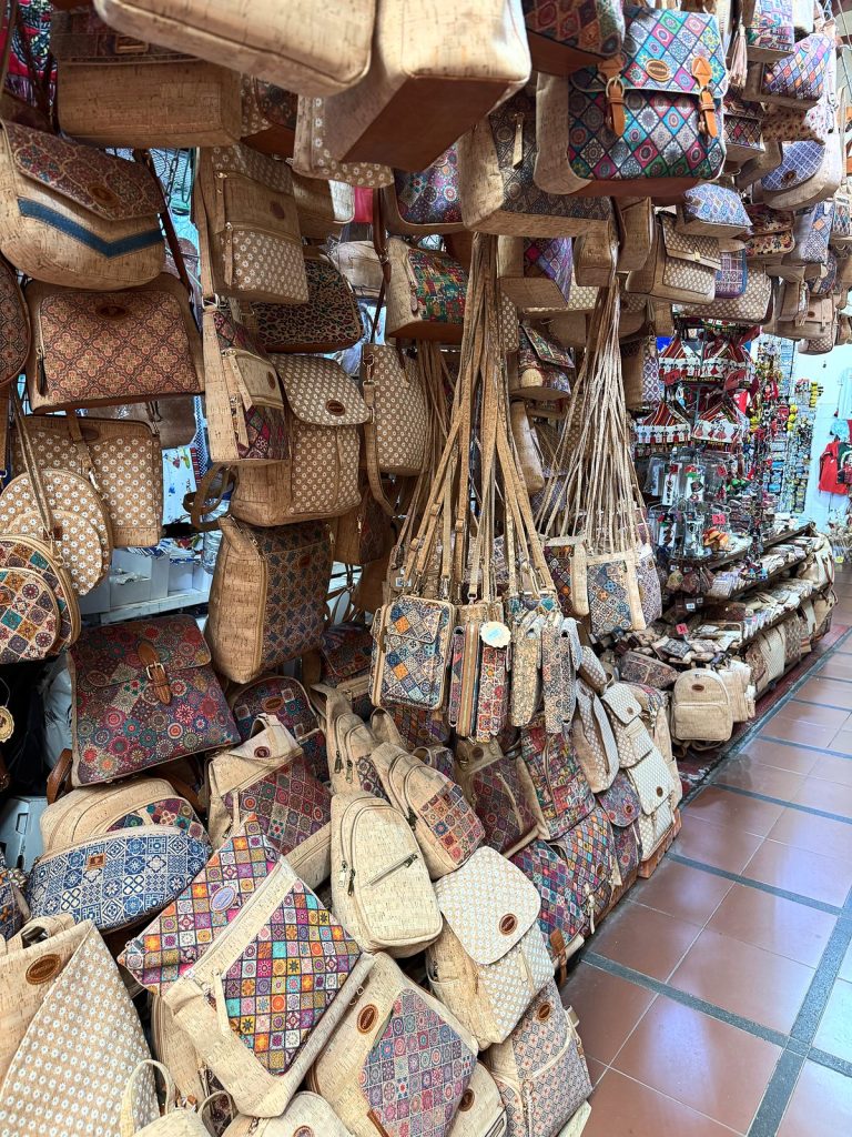 A stall with hanging cork handbags and backpacks in colourful patterns