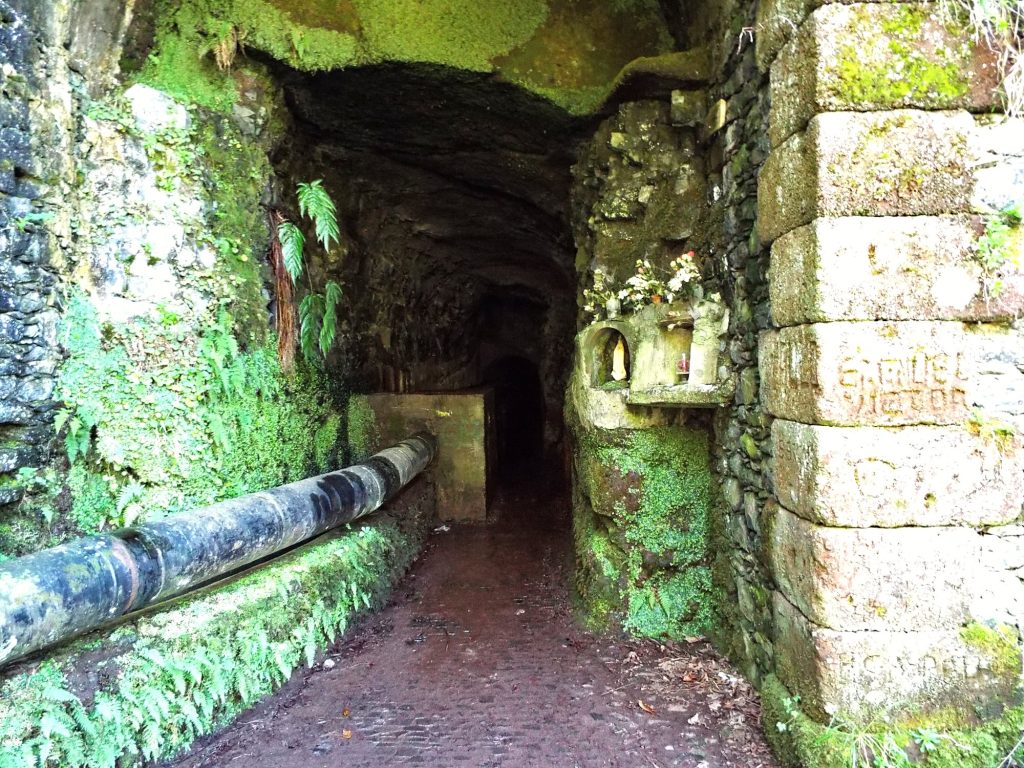 The entrance to a stone tunnel with a water pipe on the trail at Rabaçal